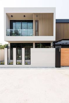 a modern house with white walls and wooden accents on the front door, along with two large garage doors