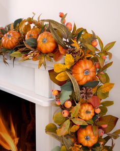 a wreath with pumpkins and leaves is hanging on the fireplace's mantel