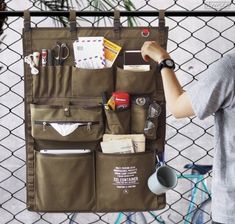 a person holding a bag with various items in it and hanging on a chain link fence