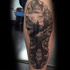 a person with a tattoo on their leg that has trees and mountains in the background