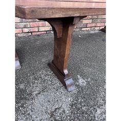 an old wooden table sitting in front of a brick wall with no one around it