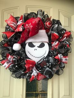 a wreath decorated with black, red and white deco mesh is hanging on the front door