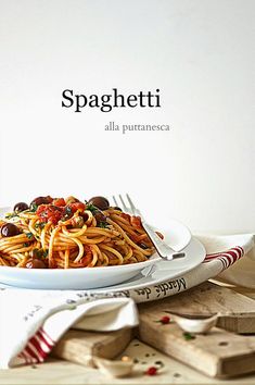 a plate of spaghetti with olives and tomatoes