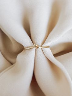 the fabric is white and has a knot at the center with a gold ring on it