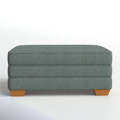 an upholstered footstool with wooden legs on a plain white background,