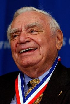 an older man with a medal around his neck smiles at the camera while wearing a suit and tie