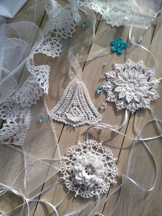 several pieces of white crocheted fabric on a wooden floor with ribbons and beads