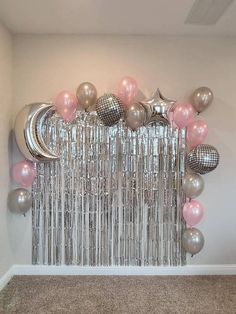 a room with balloons, stars and moon on the wall in silver and pink colors