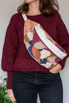 a woman wearing a red sweater holding a floral print fanny bag