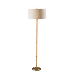 a floor lamp with a white shade on it's side and a gold base