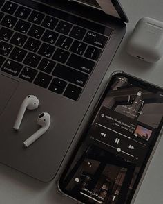 an open laptop computer sitting next to an apple airpods