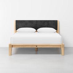 a bed with two pillows on top of it and a wooden frame around the headboard