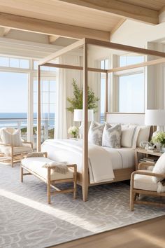 a bedroom with a four poster bed and two chairs in front of the window looking out onto the ocean