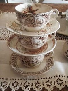 a stack of cups and saucers sitting on top of a doily covered table