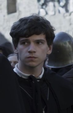 a young man standing in front of a group of people with helmets on his head