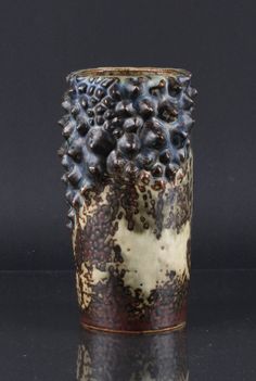 a close up of a vase on a black surface with white and brown designs in it