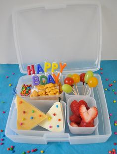 a plastic container filled with lots of food on top of a blue table covered in confetti