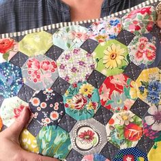 a person holding a patchwork quilt in their hands