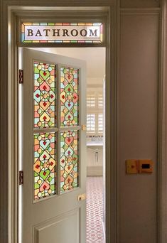 an open door leading to a bathroom with colorful stained glass panels on the front door