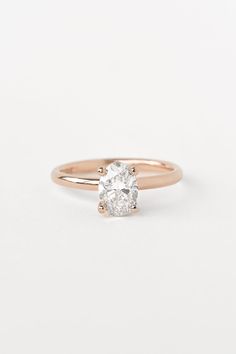 a rose gold engagement ring with an oval cut diamond in the center, on a white background