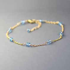 Delicate single strand bracelet created with gemstones in pretty blue color. This bracelet is made with dainty gold filled chain adorned with duos of small, faceted roundels of  London blue topaz. Gems are wrapped with gold filled wire and separated with short sections of dainty,  gold filled chain.  Adjustable from 7.5 to 8.5 inches and it closes with a gold filled lobster claw clasp. Elegant, dainty, trendy, great for layering, bracelet for any occasion. It will make a sweet gift. This style i Dainty Blue Rondelle Jewelry, Blue Beaded Bracelets With Birthstone, Blue Birthstone Round Bead Bracelets, Blue Birthstone Bracelets With Round Beads, Dainty Blue Gemstone Beaded Bracelets, Blue Birthstone Beaded Bracelets, Yellow Gold Bracelets With Blue Topaz For Gift, Dainty Blue Gemstone Bracelets, Blue Dainty Gemstone Beaded Bracelet