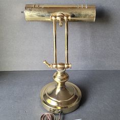 an antique brass desk lamp with cord plugged into the base and wires attached to it