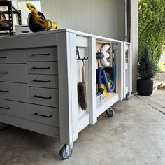 a tool cabinet with tools in it sitting on top of a garage floor next to a planter