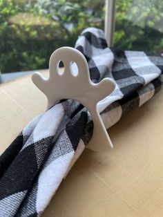 a napkin holder is sitting on top of a window sill with a black and white checkered cloth