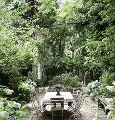 an outdoor dining table surrounded by plants and trees