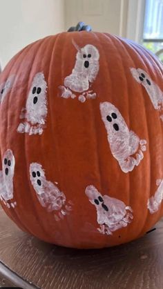 a pumpkin decorated with white ghost faces and black eyes on it's face is sitting on a table