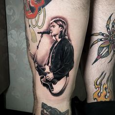 a man with tattoos on his legs has a guitar and microphone in front of him