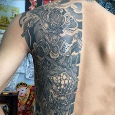 the back of a man's body with tattoos on his upper half and chest