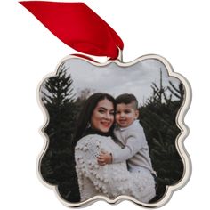 a christmas ornament with a red ribbon hanging from it's side and an image of a woman holding a baby