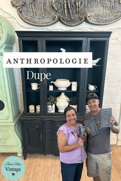 two people standing next to each other in front of a display case with antiques on it