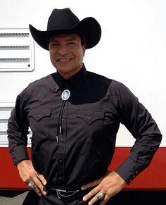 a man wearing a cowboy hat standing in front of a bus