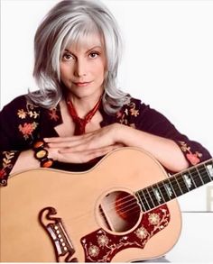 a woman with grey hair holding an acoustic guitar