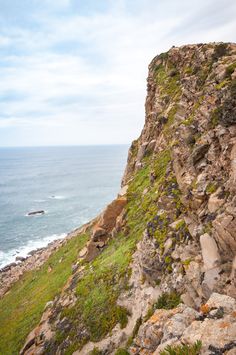 a man standing on top of a cliff next to the ocean