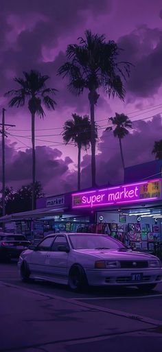 cars parked in front of a super market with palm trees and purple sky behind them