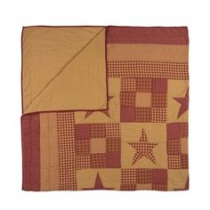 a red and tan quilt with stars on it, sitting next to a white wall