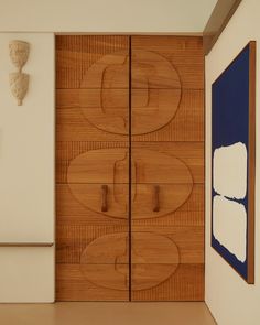 a wooden cabinet in a room with artwork on the wall