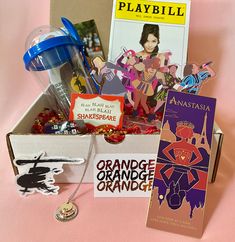 an open box filled with assorted items on top of a pink cloth covered table