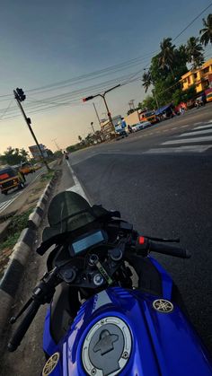 a blue motorcycle parked on the side of a road next to a street sign and traffic light