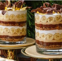 two desserts with chocolate and banana slices in them sitting on gold platters next to each other