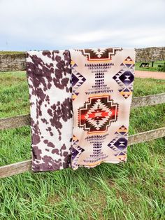 two blankets hanging on a fence in the grass