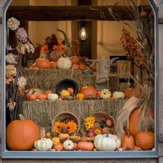 pumpkins and gourds are arranged on hay bales in an outdoor display