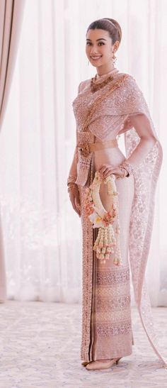 a woman in a pink and gold sari with her hands on her hips, posing for the camera