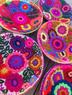 four colorful bowls are sitting on a wooden table and one is made out of yarn