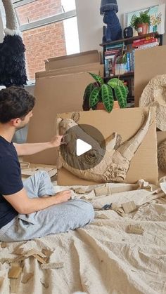 a man sitting on top of a bed in front of cardboard boxes and an ostrich