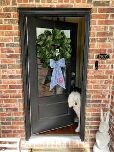 a dog is standing in front of a door with a bow on it's head