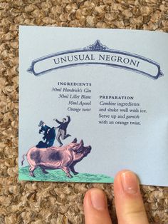 a hand holding up a business card with an image of a pig on it's back